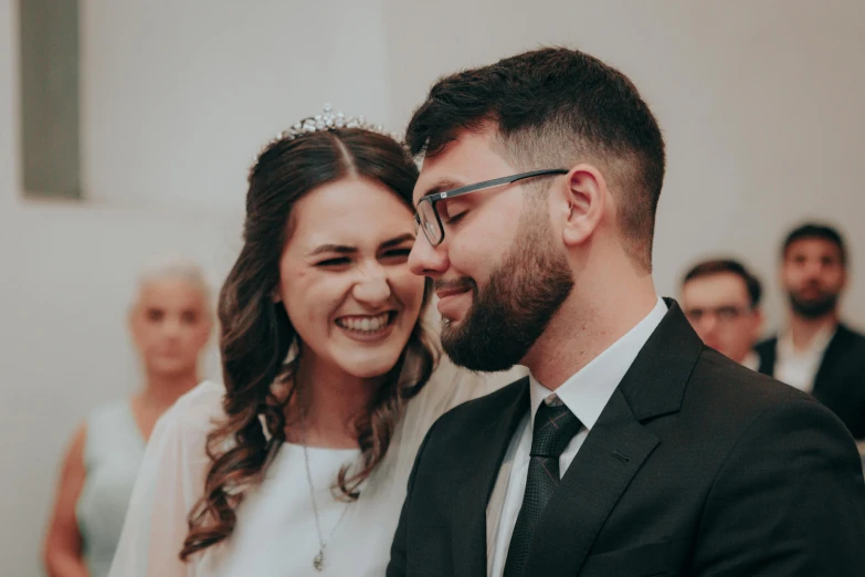 a man and woman smiling at each other with a bridal crowd behind them