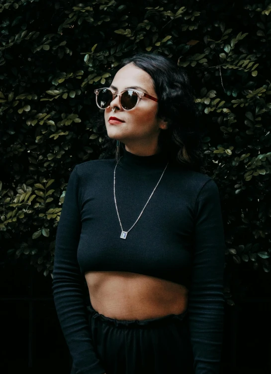 a young woman in black wearing a sweater and sunglasses
