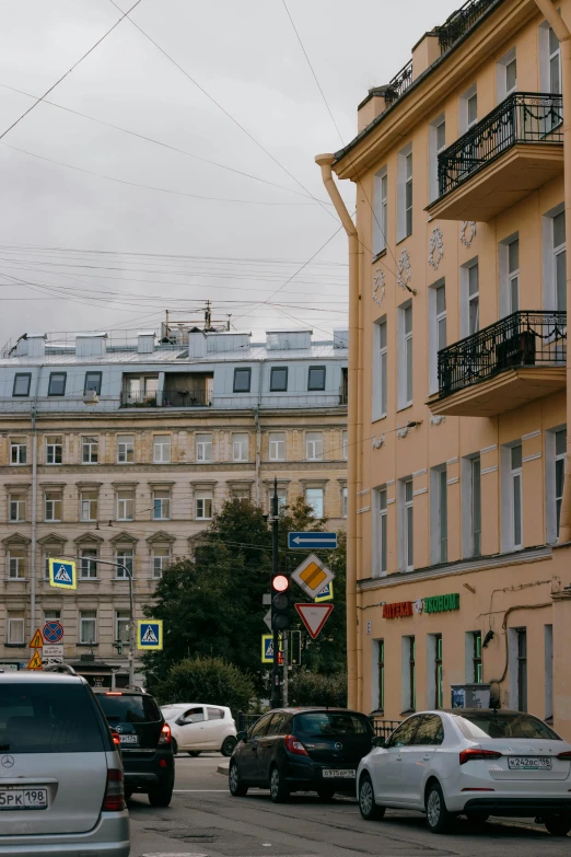 several cars are driving in a busy street near some buildings