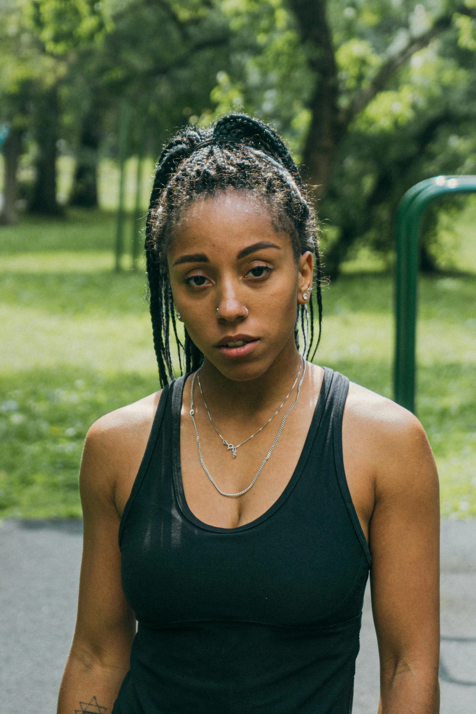 a woman standing in the park wearing a black tank top