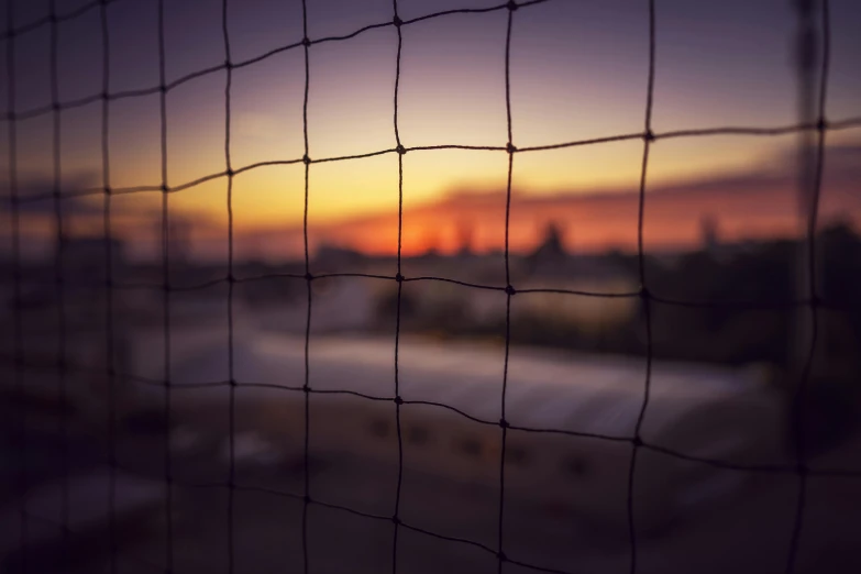 blurred sunset and buildings with a wire fence