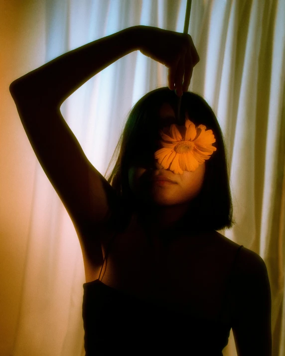 woman in black dress holding a orange flower