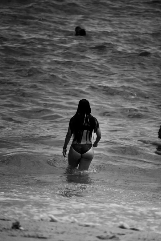 a woman stands in the ocean water wearing a bikini