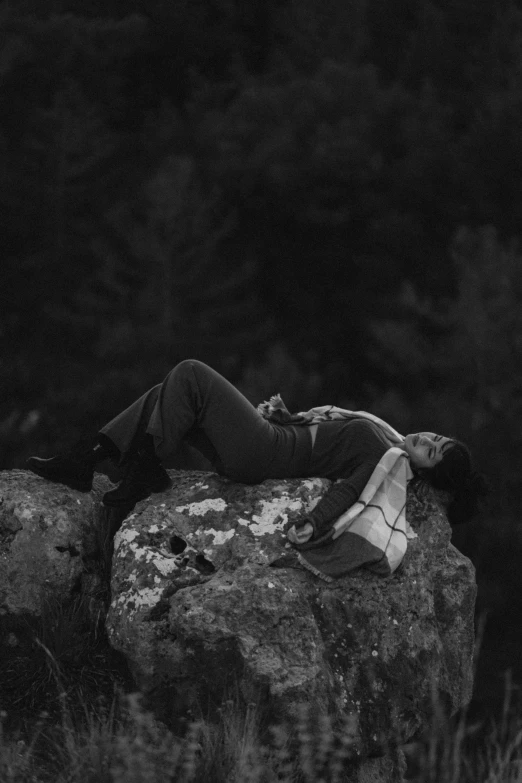 a person lying on a rock in a field