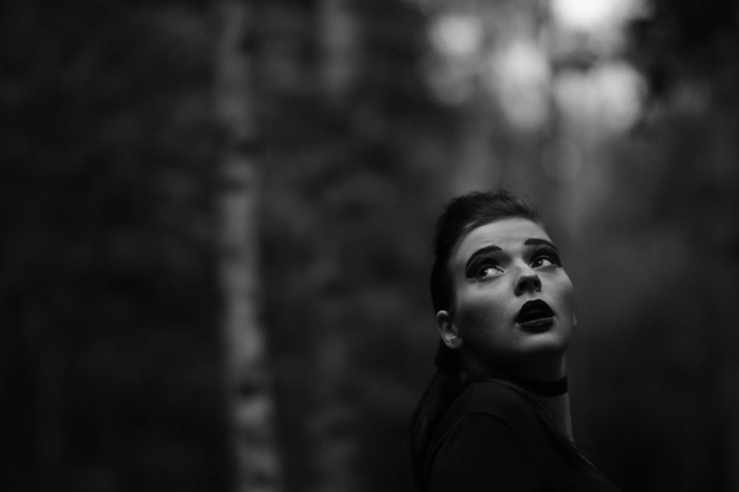 a woman standing in a forest staring up