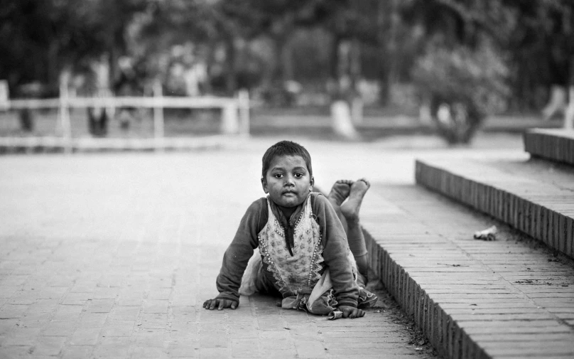 a child with a sad look sitting on the pavement