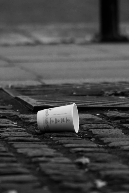 a black and white po of a paper cup laying on a street