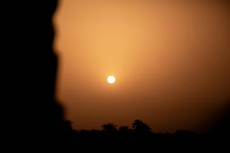 a silhouetted person looks at a partial sun as the eclipse is over the horizon