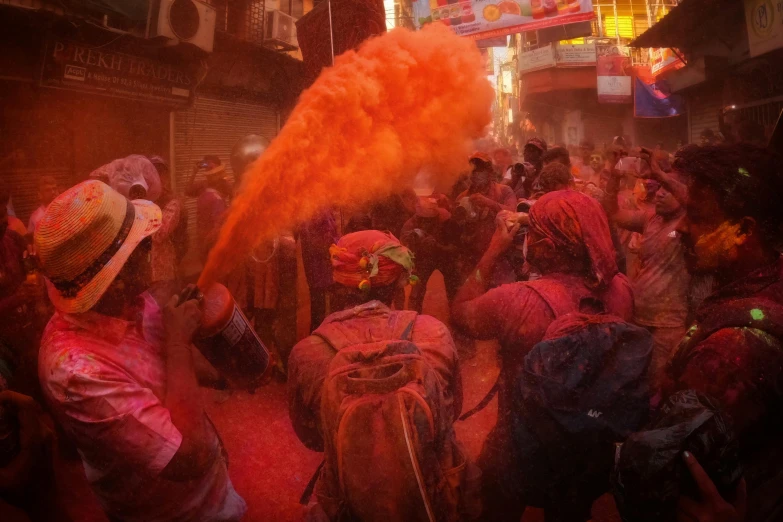 a crowd is covered in colorful orange powder and surrounded by people