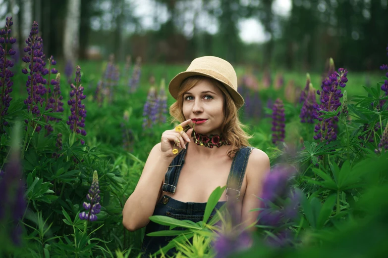 a young woman wearing a straw hat poses for a picture among lupine flowers