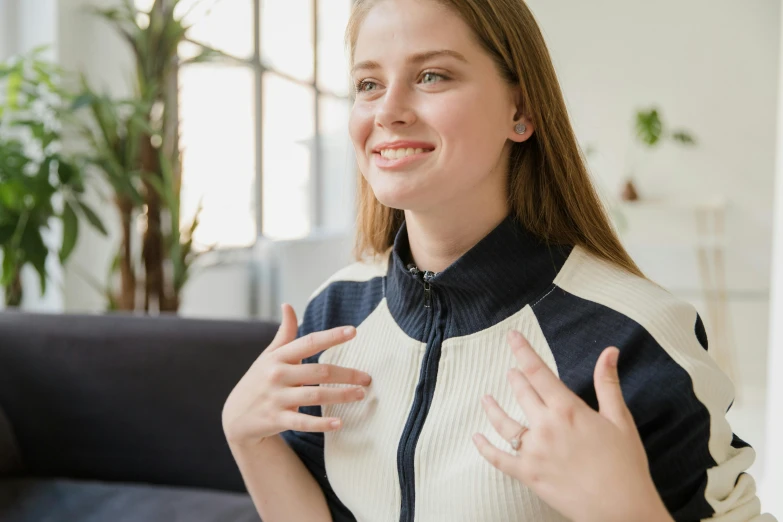 a woman with a white and black sweater is giving a peace sign