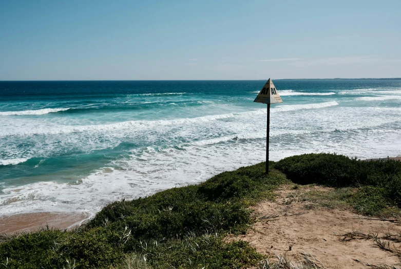 a small road leads into the ocean and is under an umbrella