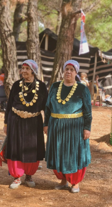 two women are standing in front of a tree