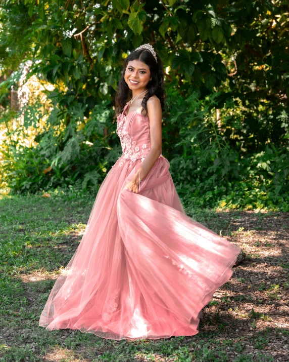 a girl poses in a pink dress on a grassy field