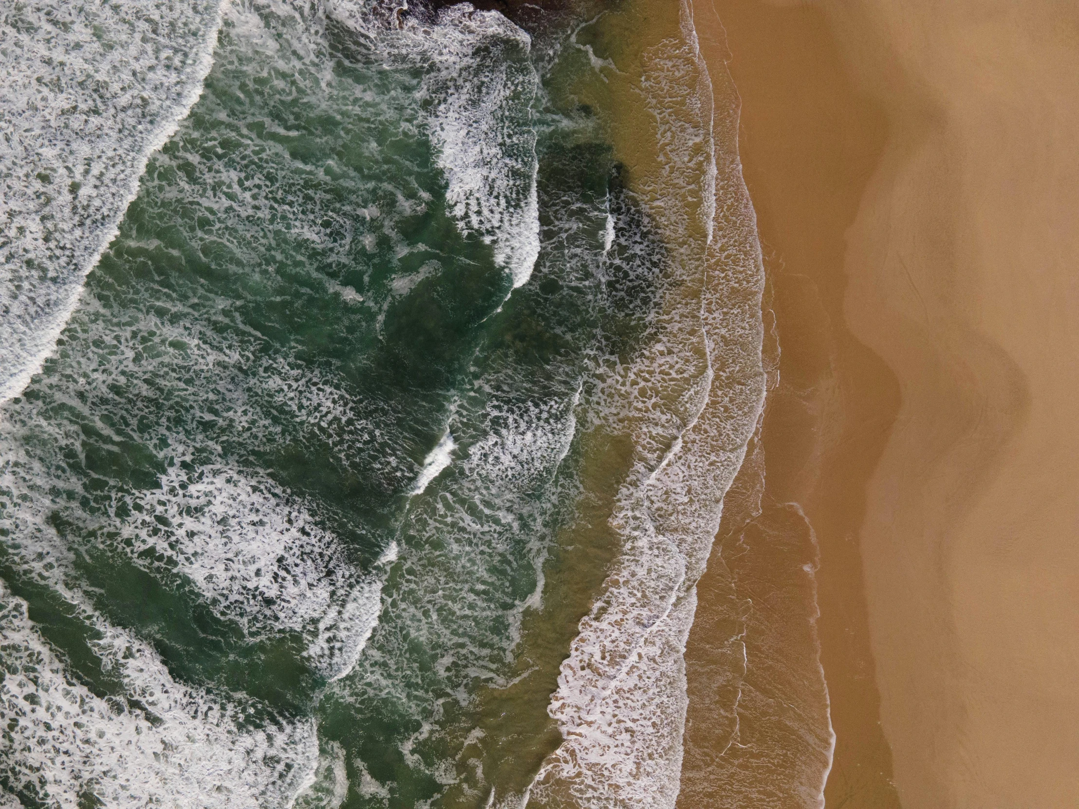 water and sand waves at the beach, aerial view