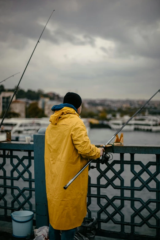 person fishing on the side of a bridge with a body of water in the background