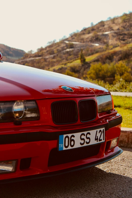 a red bmw on the side of a road