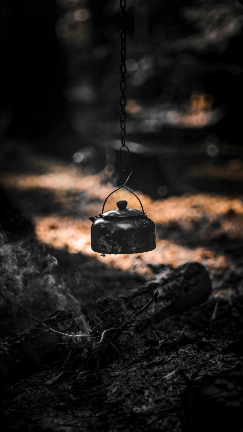 a tea kettle hanging from a chain in the dark