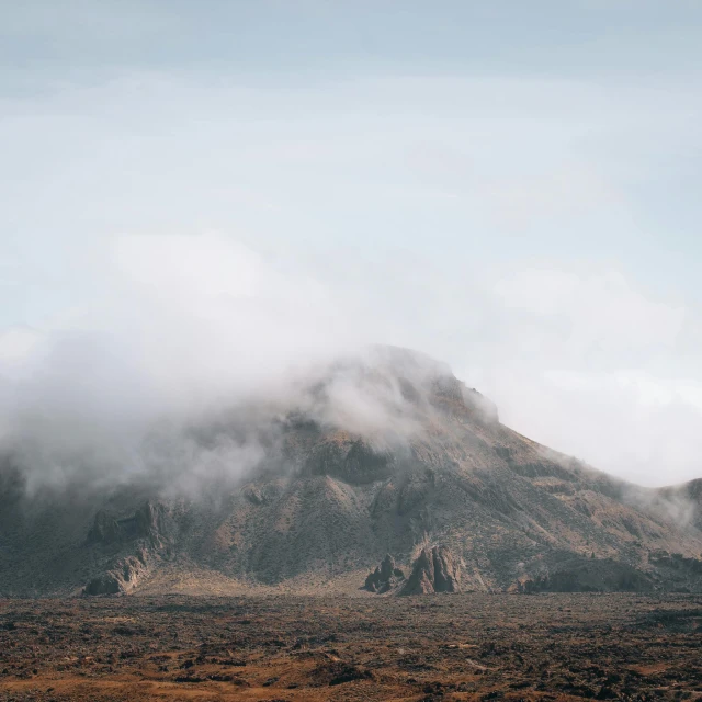 a mountain covered with mist and fog on a cloudy day