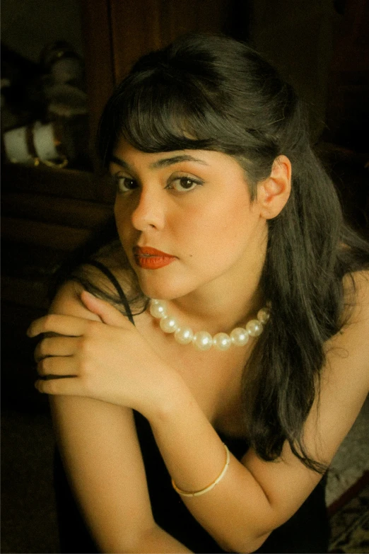 an attractive woman in pearls and celets posing for the camera