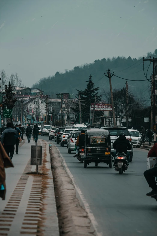 a busy city street filled with cars, motorcycles, and pedestrians