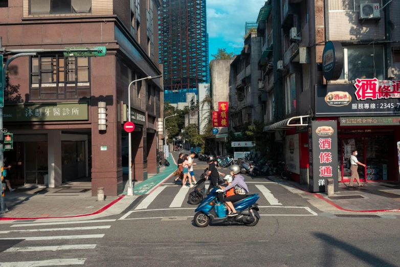 many people riding scooters down a street lined with buildings