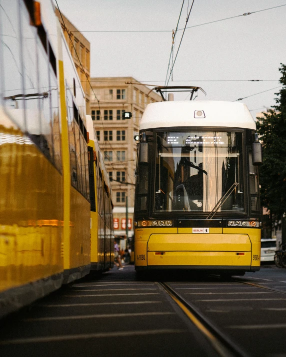 yellow bus driving down street next to a tall building