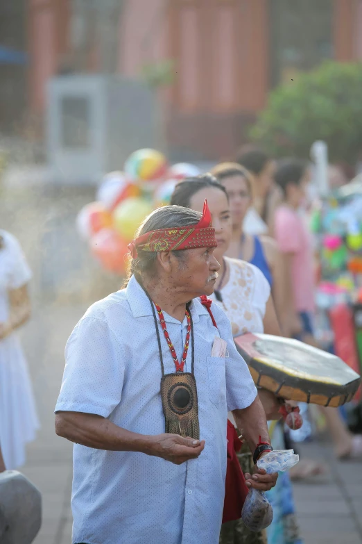 a woman in a red flower headdress carrying a drum