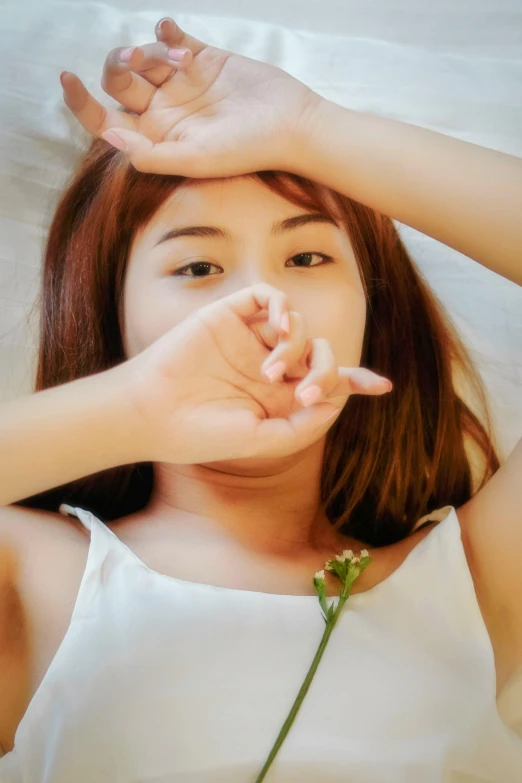 a girl laying in bed with her hands on top of a flower