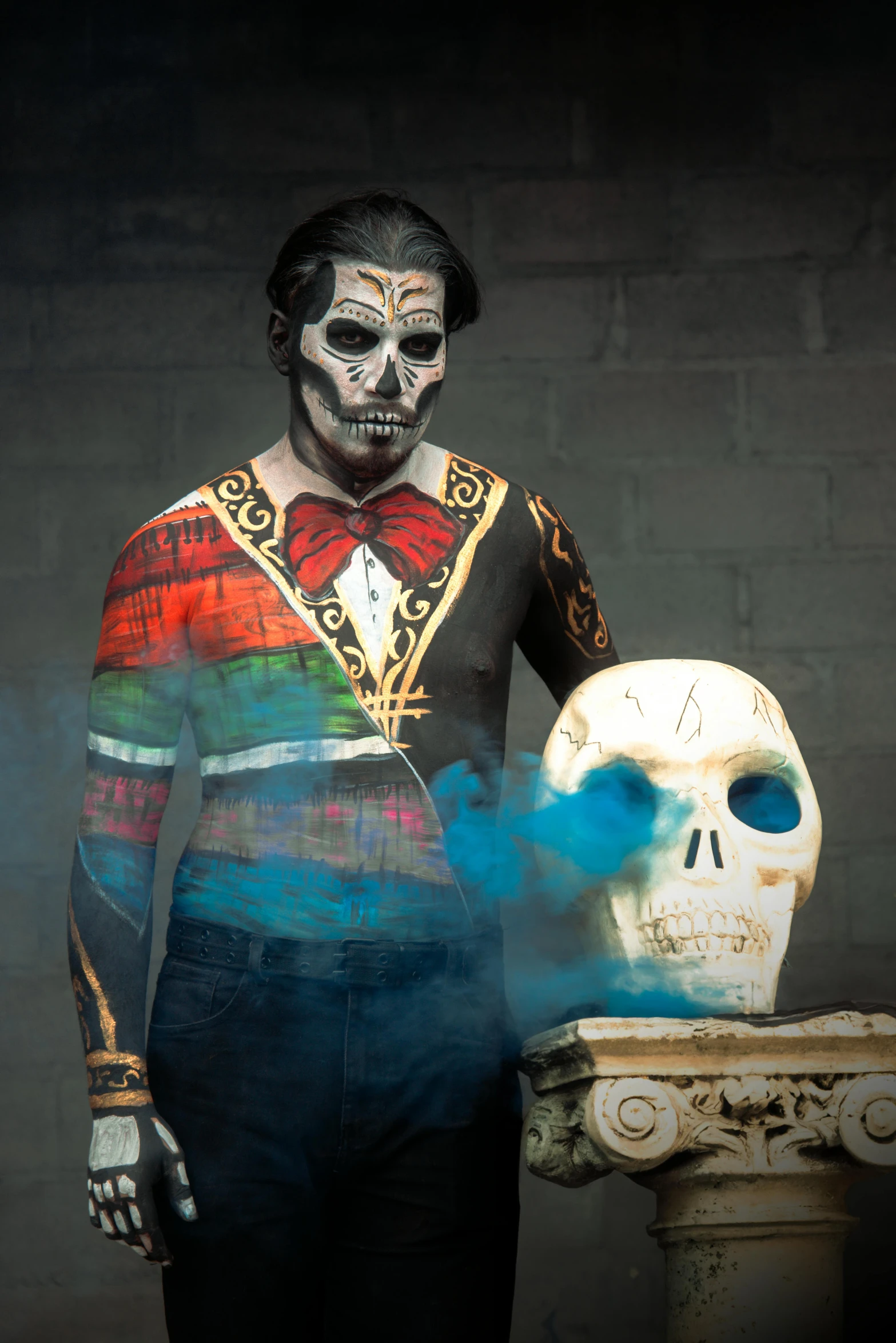 a man wearing makeup standing next to a skull