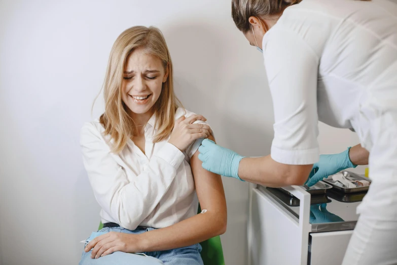 a woman in white blouse getting her arm cut