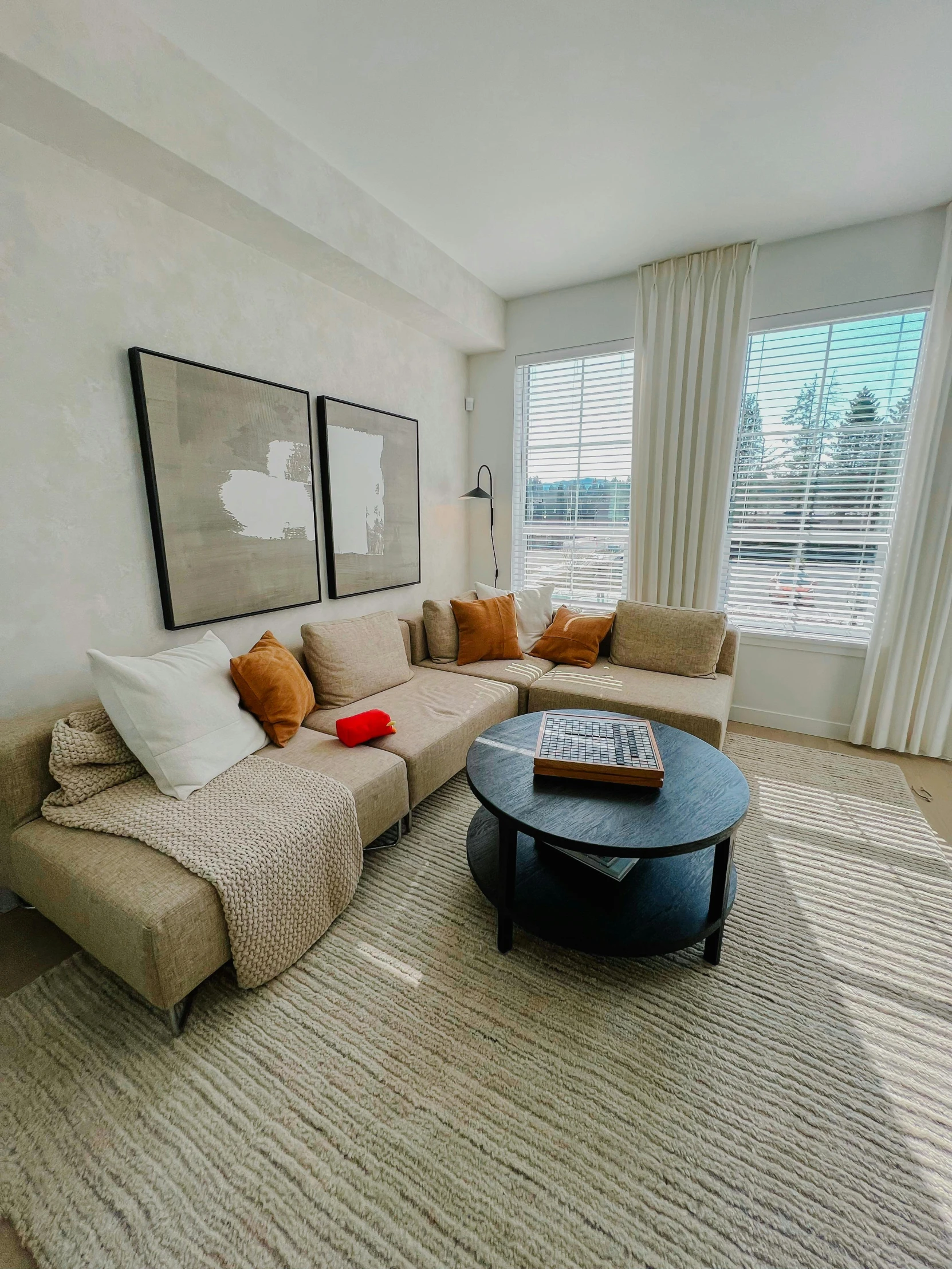 a room with a couch, table and two large windows