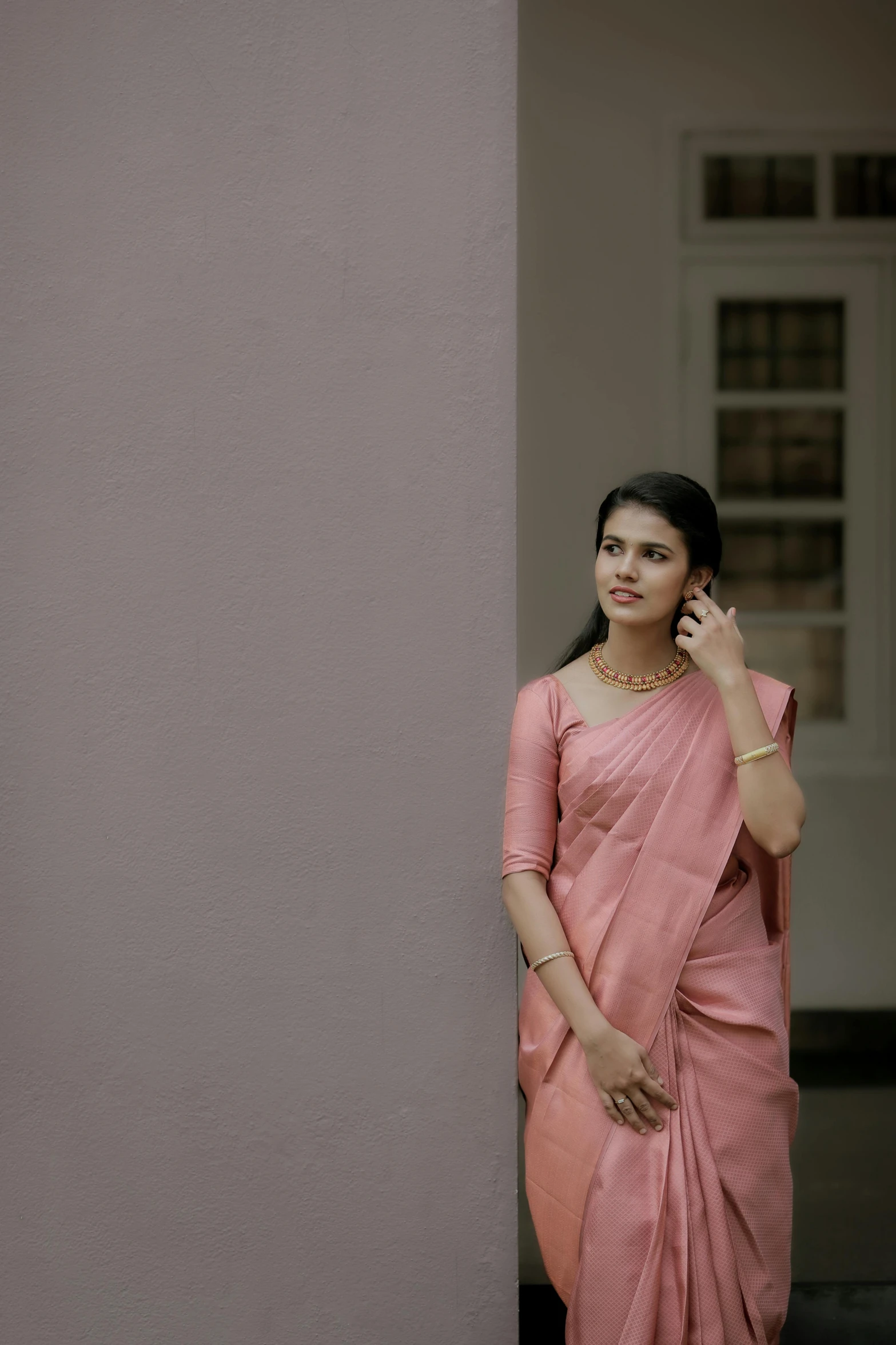 a young woman wearing a pink sari and holding a cell phone