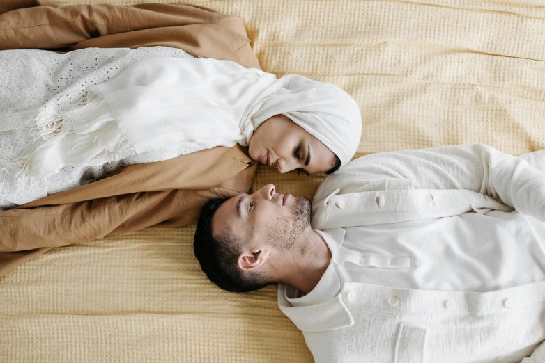 a man lays in bed wearing white clothes