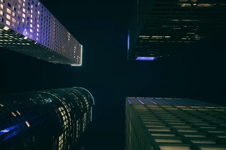 two skyscrs at night with one building lighting up