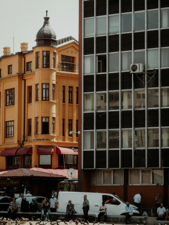 many people are standing outside a tall yellow building