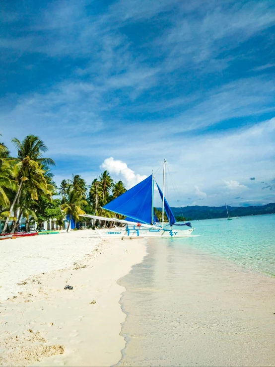 a sailboat is sitting on the beach in clear blue water