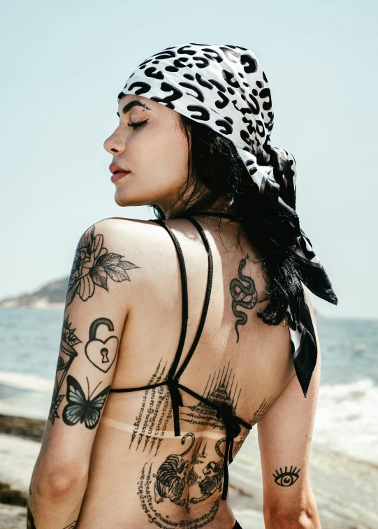 a tattooed woman sitting on the beach