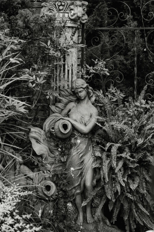 a garden statue surrounded by flowers and foliage