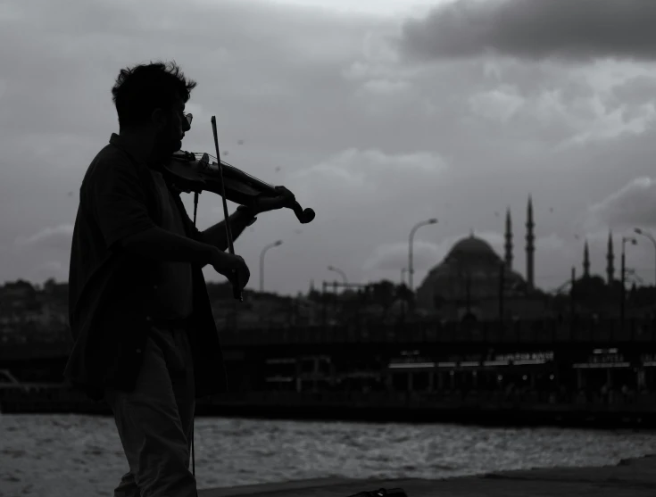 the musician is playing the violin by the water