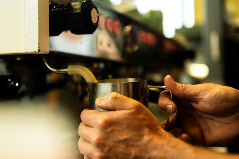 a person holding up a coffee cup to a machine