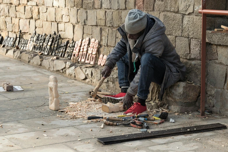 a man sitting on the side of a building next to some tools