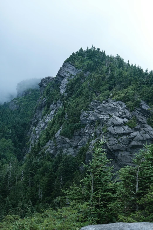 fog hangs over the top of a rocky mountain