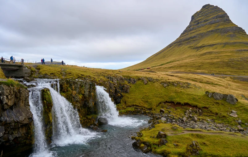 people in the background standing on rocks and a waterfall