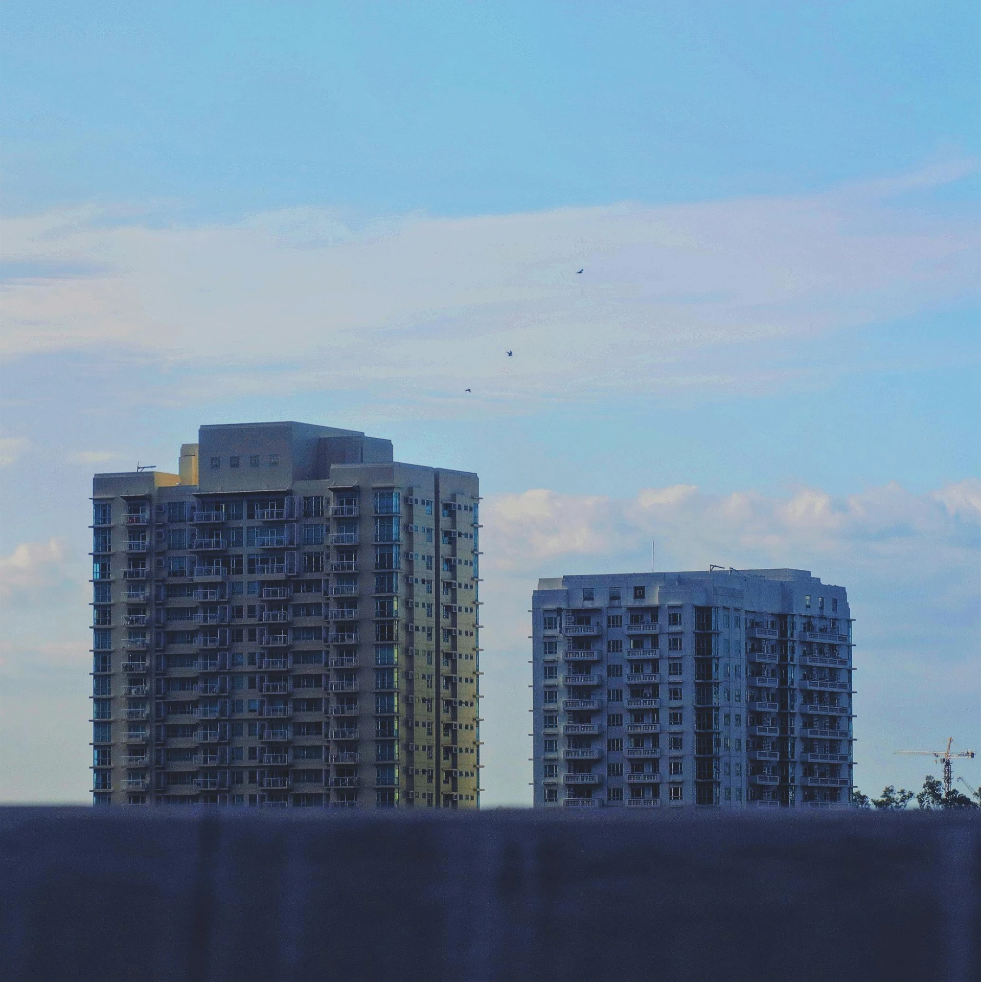 some tall buildings on a street with cloudy sky