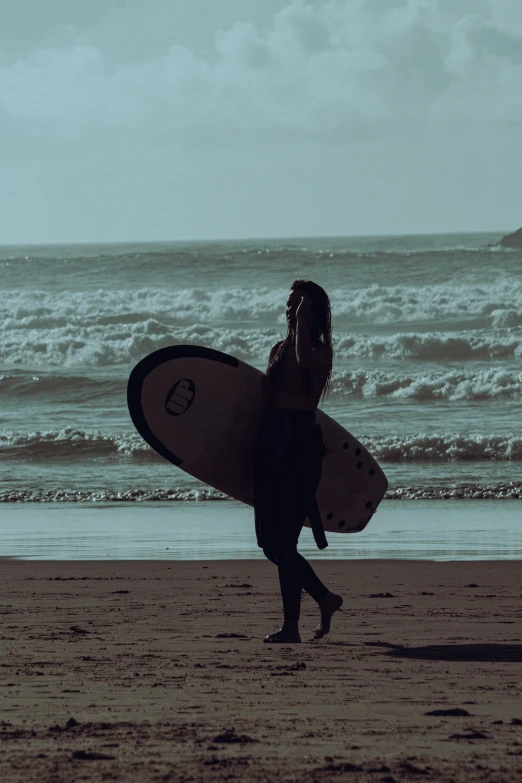 a woman walking on the beach with a surfboard
