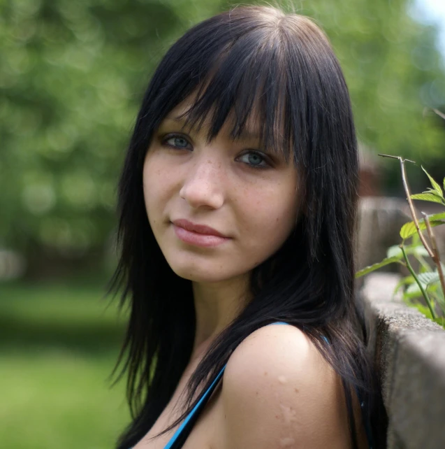 a beautiful woman standing next to a brick wall in the grass