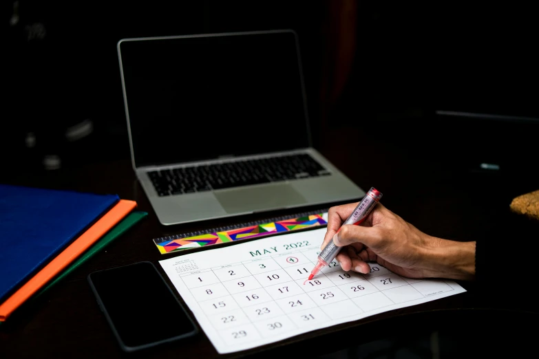 someone is sitting at a table and holding a pen