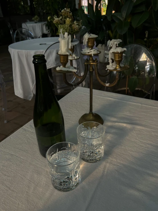 a table with bottles and glasses, a candle, and a chandelier