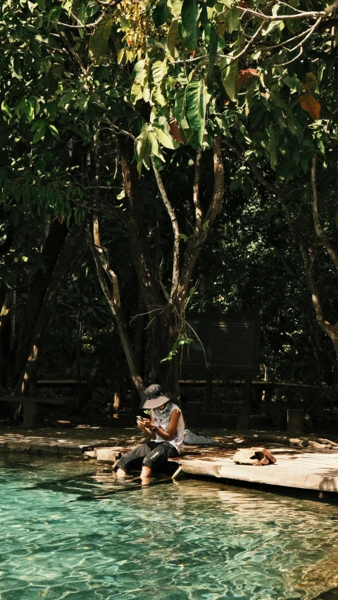 there is a man sitting on a log in the middle of a lake